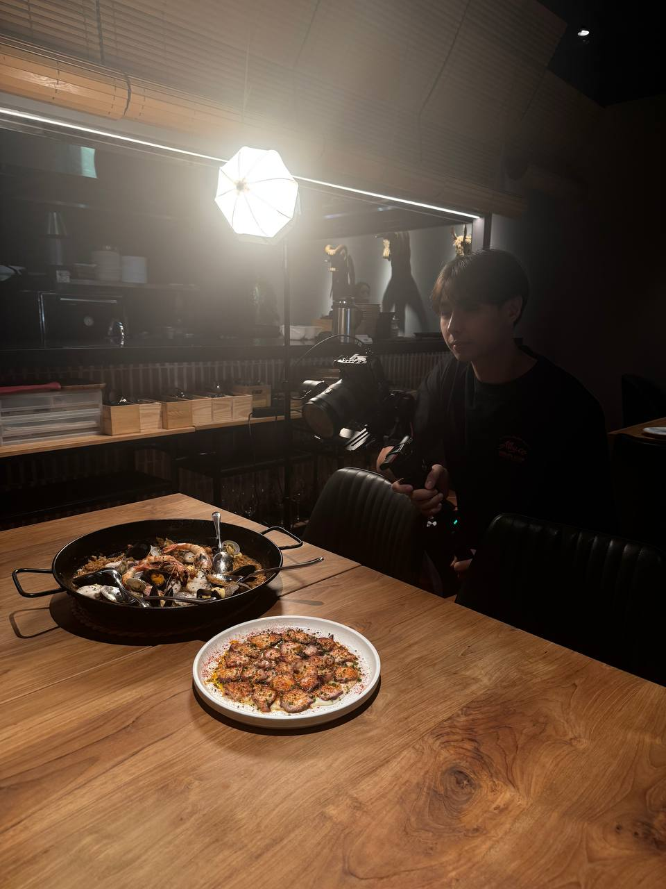 Filming a seafood paella on a wooden table under a continuous studio light